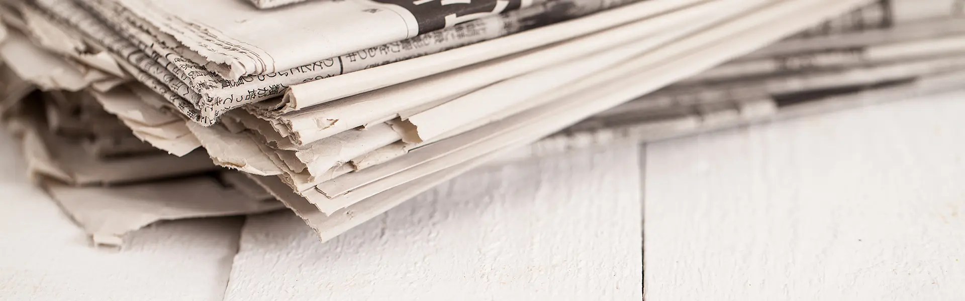 A pile of newspapers on a wooden table