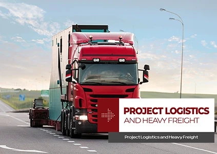 A red truck with a lowbed that says "Project and Heavy Load Transportation" on it is moving on the highway